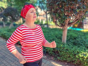 An empowered woman in a red-striped shirt is walking.