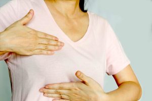 A closeup of a woman holding both hands over her breast.