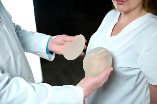 Plastic surgeon holds silicone breast implants.